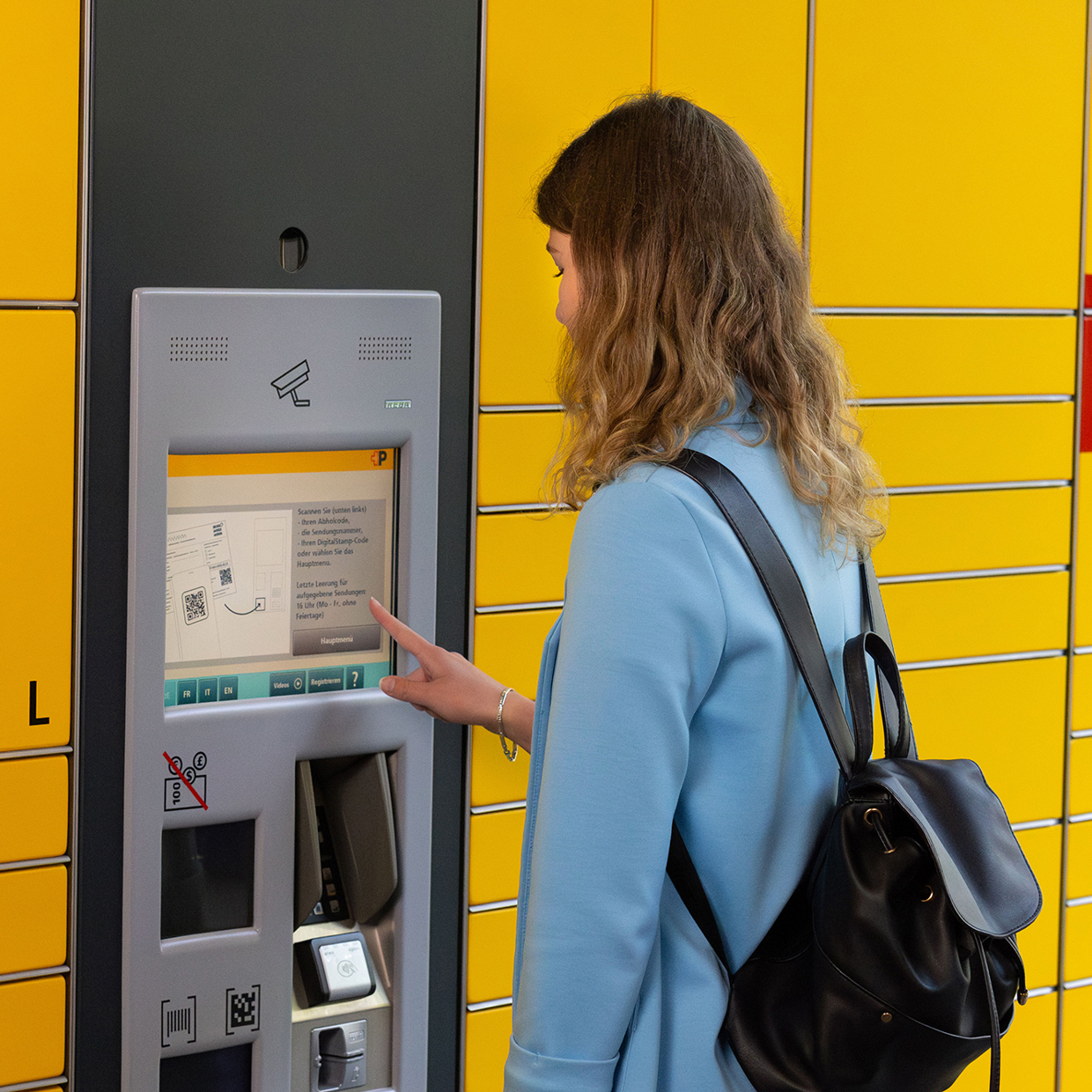 Eine Frau gibt an einem Paketautomaten ein Paket ab